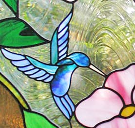 Closeup of custom stained and leaded glass hummingbird and flowers window
