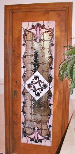 Victorian style stained and leaded glass custom door window separating a walk-in closet and bathroom